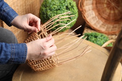 Woman weaving wicker basket indoors, closeup view