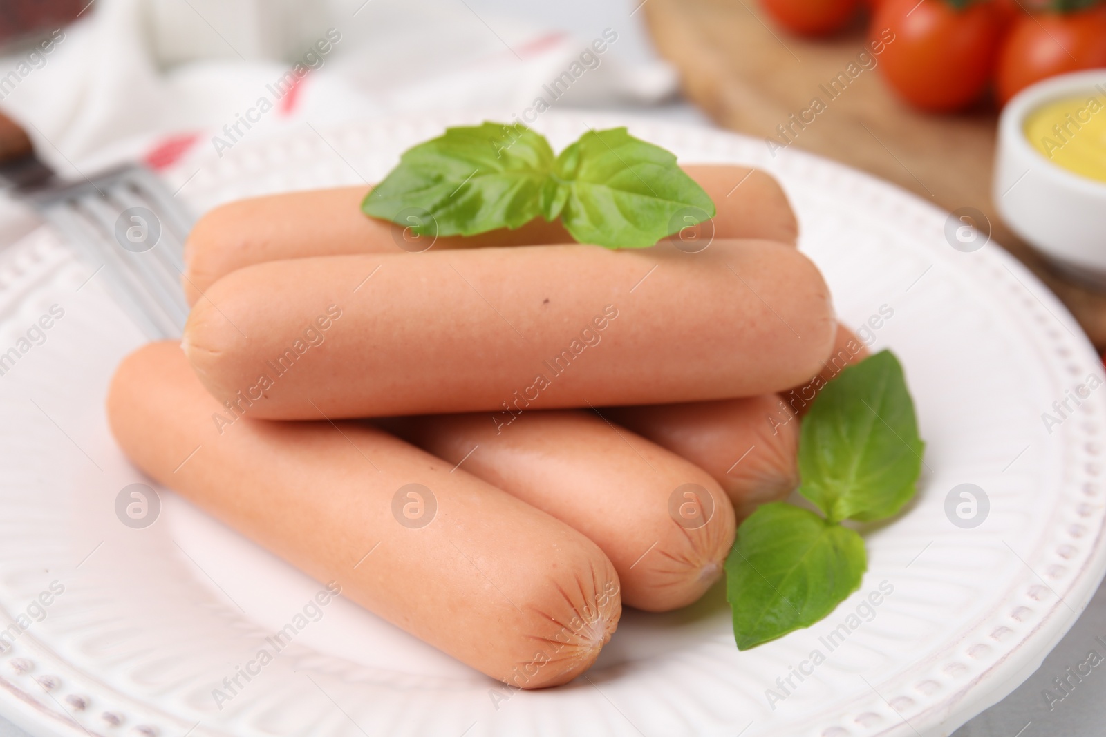 Photo of Delicious boiled sausages and basil on plate, closeup