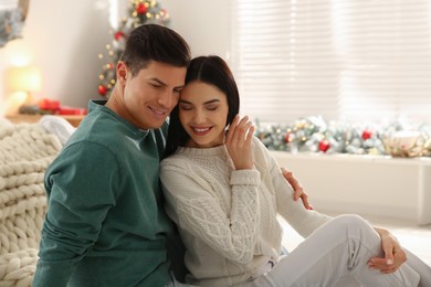 Happy couple sitting on floor at home. Christmas celebration