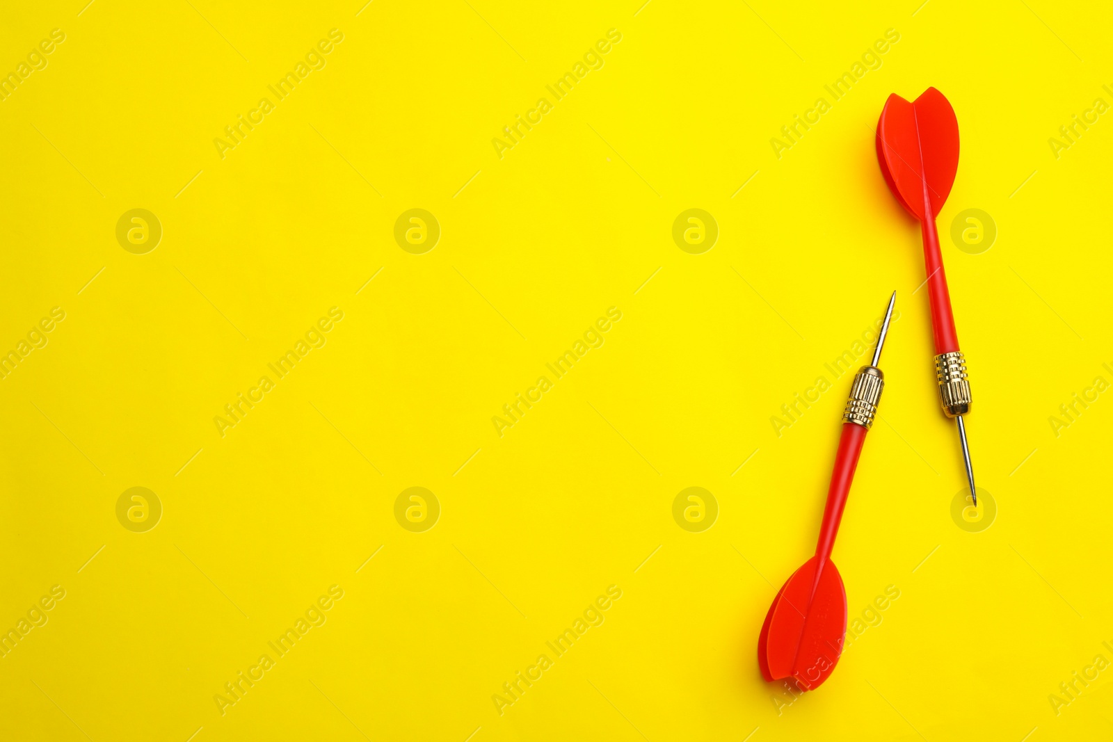 Photo of Red dart arrows on yellow background, flat lay with space for text