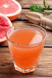 Photo of Tasty freshly made grapefruit juice on wooden table