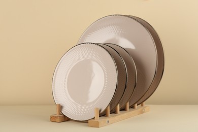 Photo of Drying rack with beige ceramic plates on pale yellow table