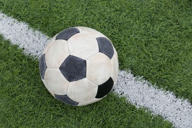 Photo of Dirty soccer ball on green football field, closeup