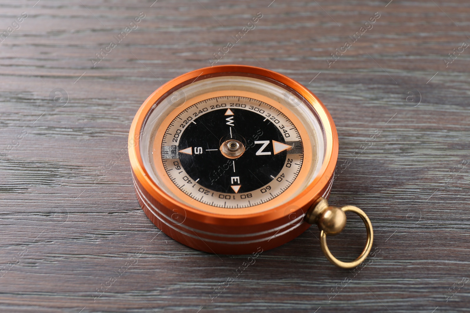 Photo of One compass on wooden table, closeup. Tourist equipment