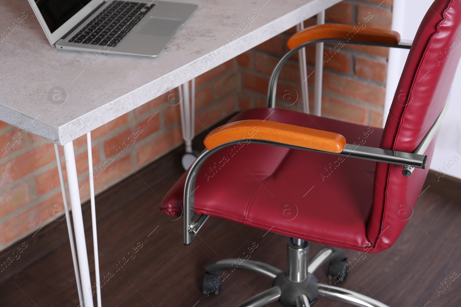 Photo of Comfortable red desk chair near table with laptop in modern office