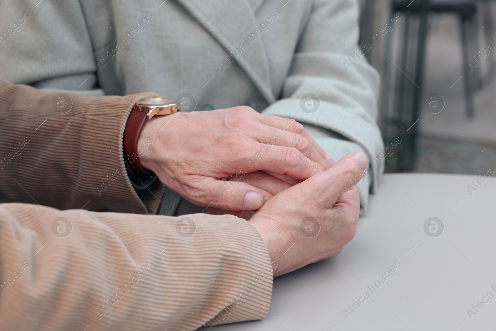 Photo of Affectionate senior couple sitting at table outdoors, closeup