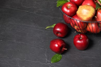 Photo of Fresh red apples and leaves on dark grey table. Space for text