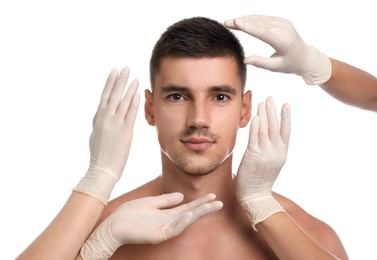 Photo of Doctors examining man's face for cosmetic surgery on white background