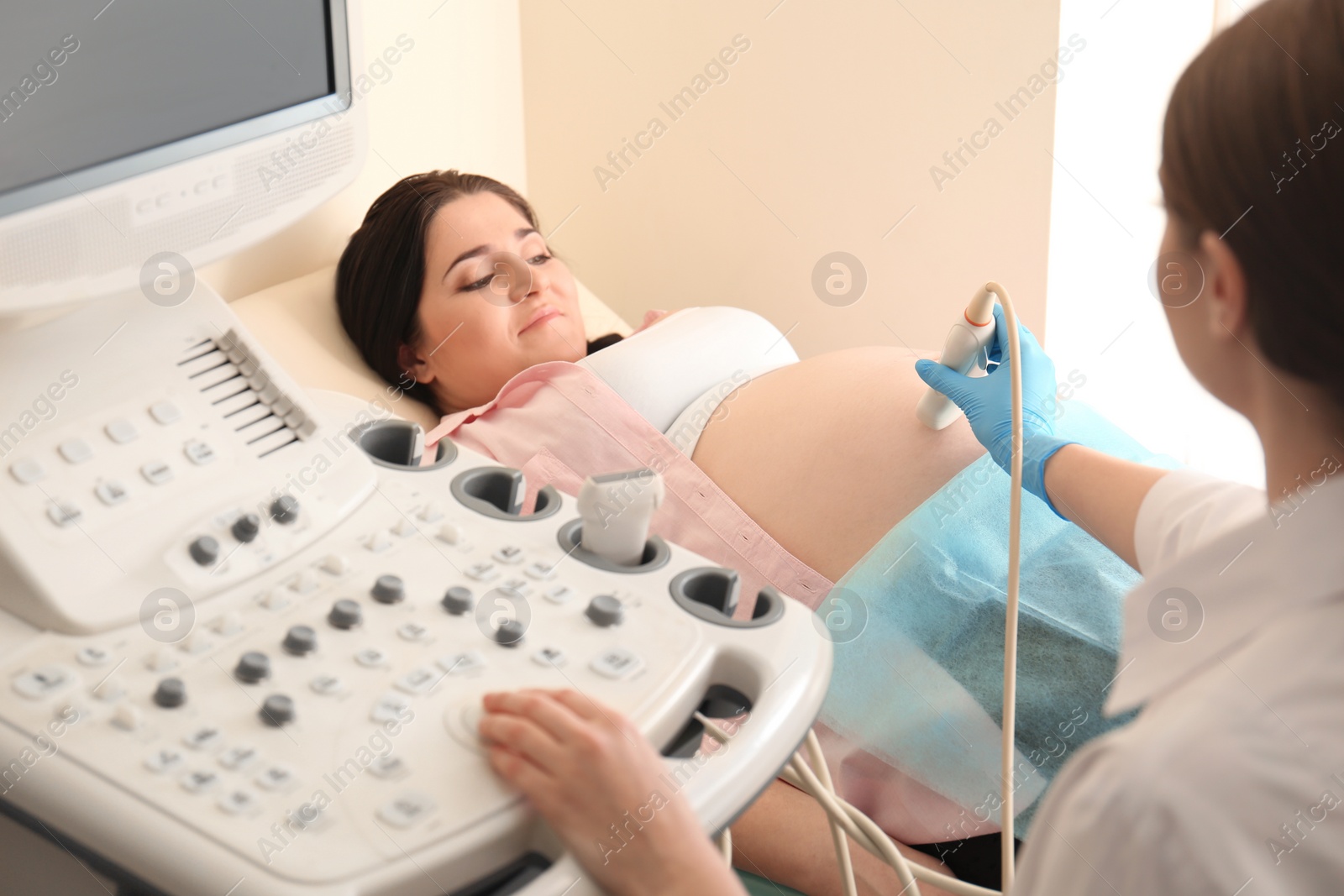 Photo of Young pregnant woman undergoing ultrasound scan in clinic