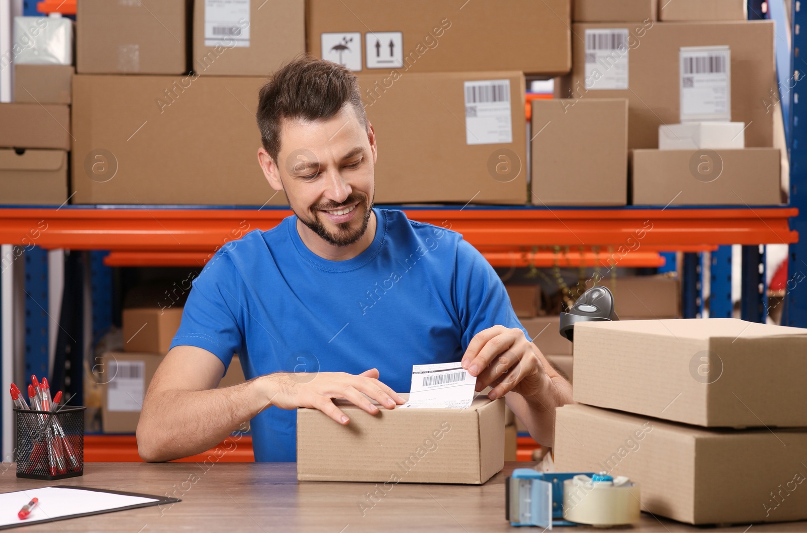 Photo of Post office worker sticking barcode on parcel at counter indoors