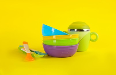 Set of plastic dishware on yellow background. Serving baby food