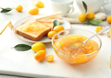 Delicious kumquat jam, fresh fruits and sandwiches on white tray