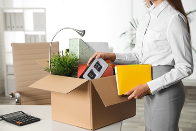 Photo of Young woman packing stuff in box at office, closeup