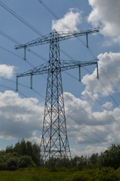 Modern high voltage tower in field on sunny day