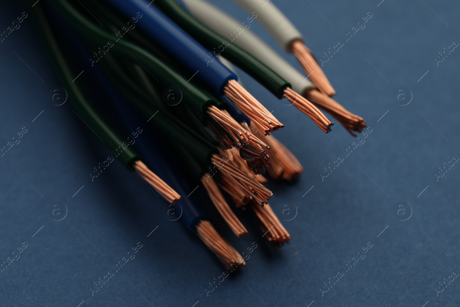 Photo of Electrical wires on blue background, closeup view