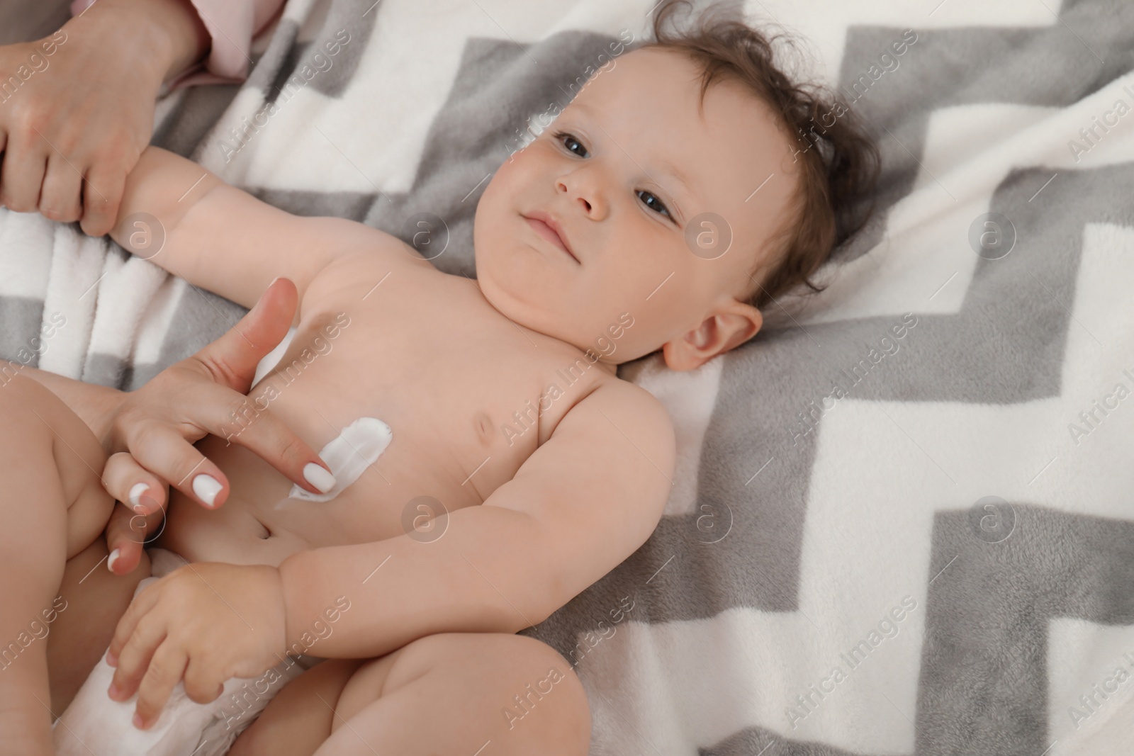 Photo of Mother applying body cream on her baby, above view