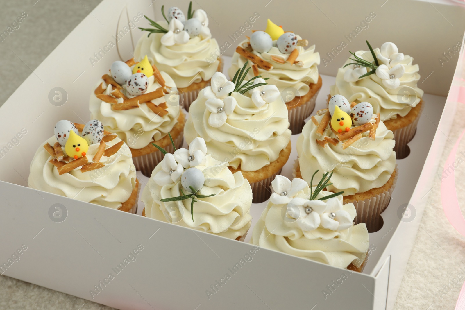 Photo of Tasty Easter cupcakes with vanilla cream in box, closeup