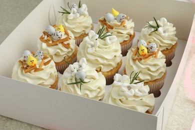 Photo of Tasty Easter cupcakes with vanilla cream in box, closeup