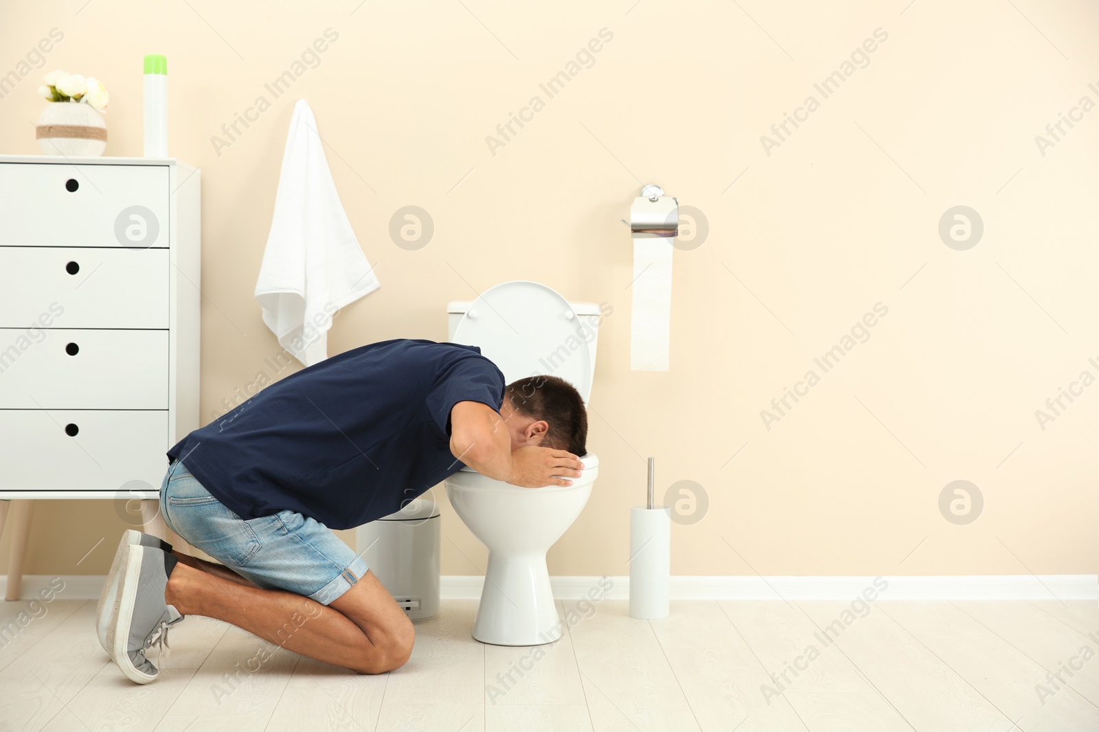 Photo of Young man vomiting in toilet bowl at home