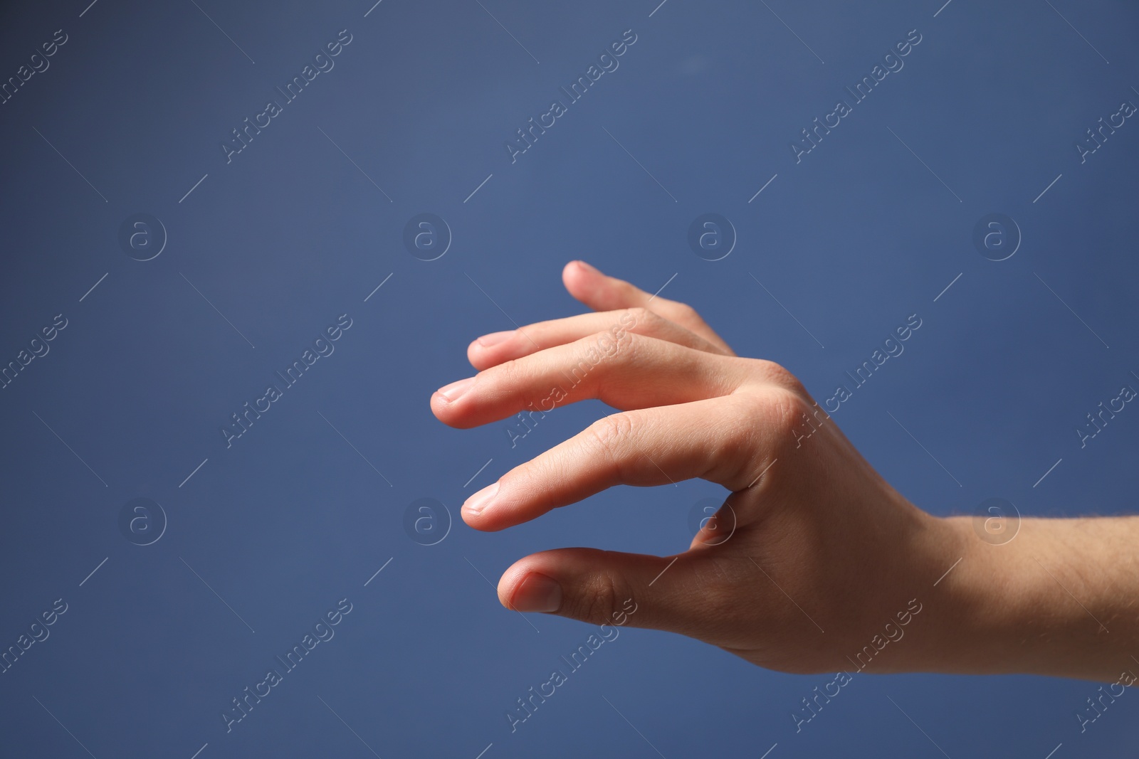 Photo of Man holding something in hand on blue background, closeup