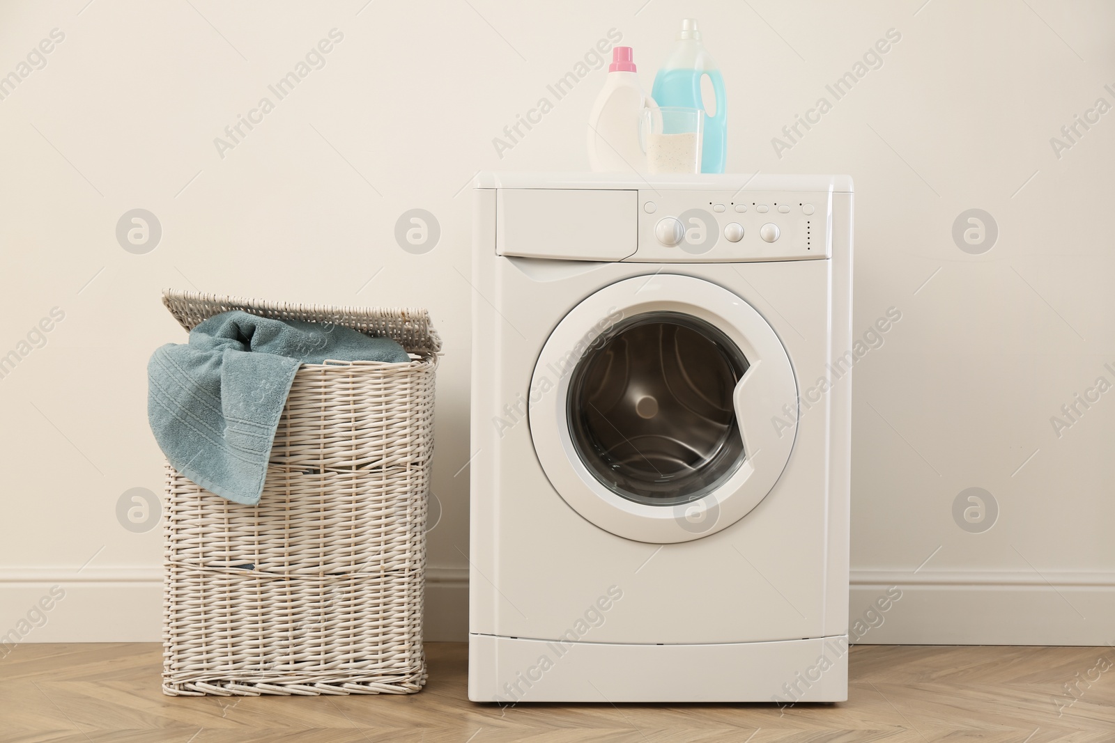 Photo of Laundry room interior with modern washing machine and wicker basket near white wall