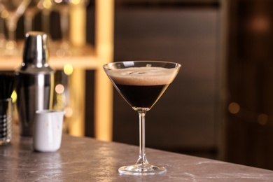 Photo of Glass of delicious Espresso Martini on bar counter. Alcohol cocktail