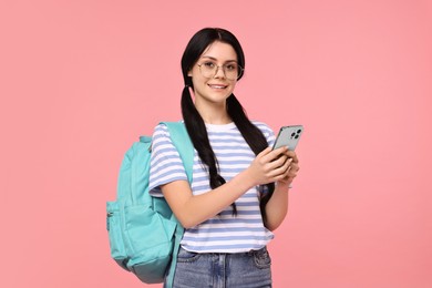 Photo of Smiling student with smartphone and backpack on pink background