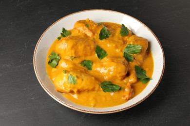 Photo of Tasty chicken curry with parsley on black textured table