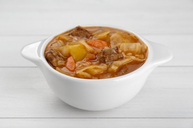 Tasty cabbage soup with meat and carrot on white wooden table, closeup