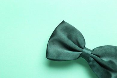 Photo of Stylish satin bow tie on light green background, top view. Space for text