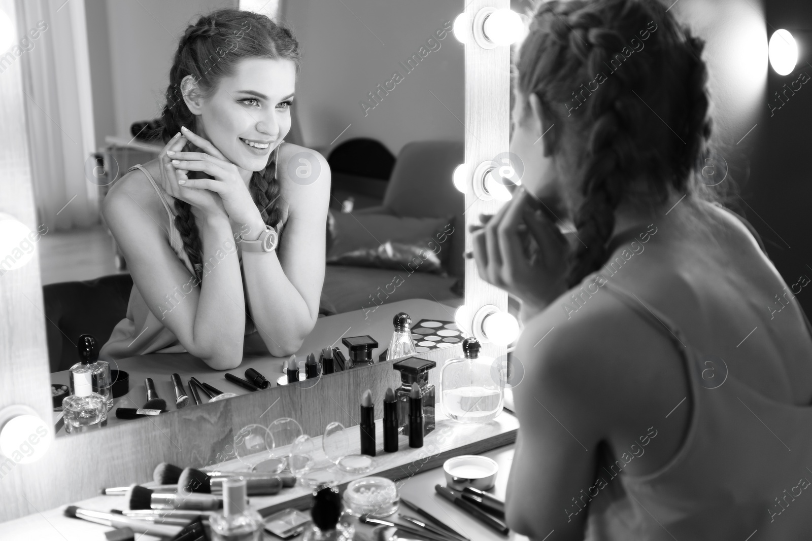 Photo of Portrait of beautiful woman with natural makeup near mirror indoors, black and white effect