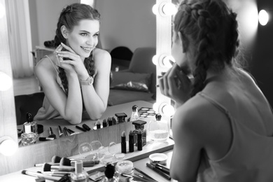 Portrait of beautiful woman with natural makeup near mirror indoors, black and white effect