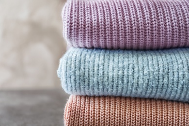 Photo of Stack of warm knitted clothes on grey background