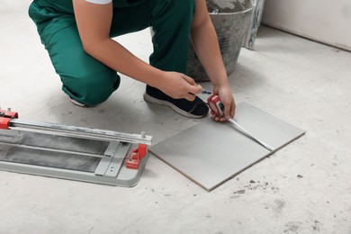 Photo of Worker measuring ceramic tile on floor, closeup