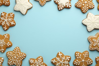 Frame made of tasty star shaped Christmas cookies with icing on light blue background, flat lay. Space for text