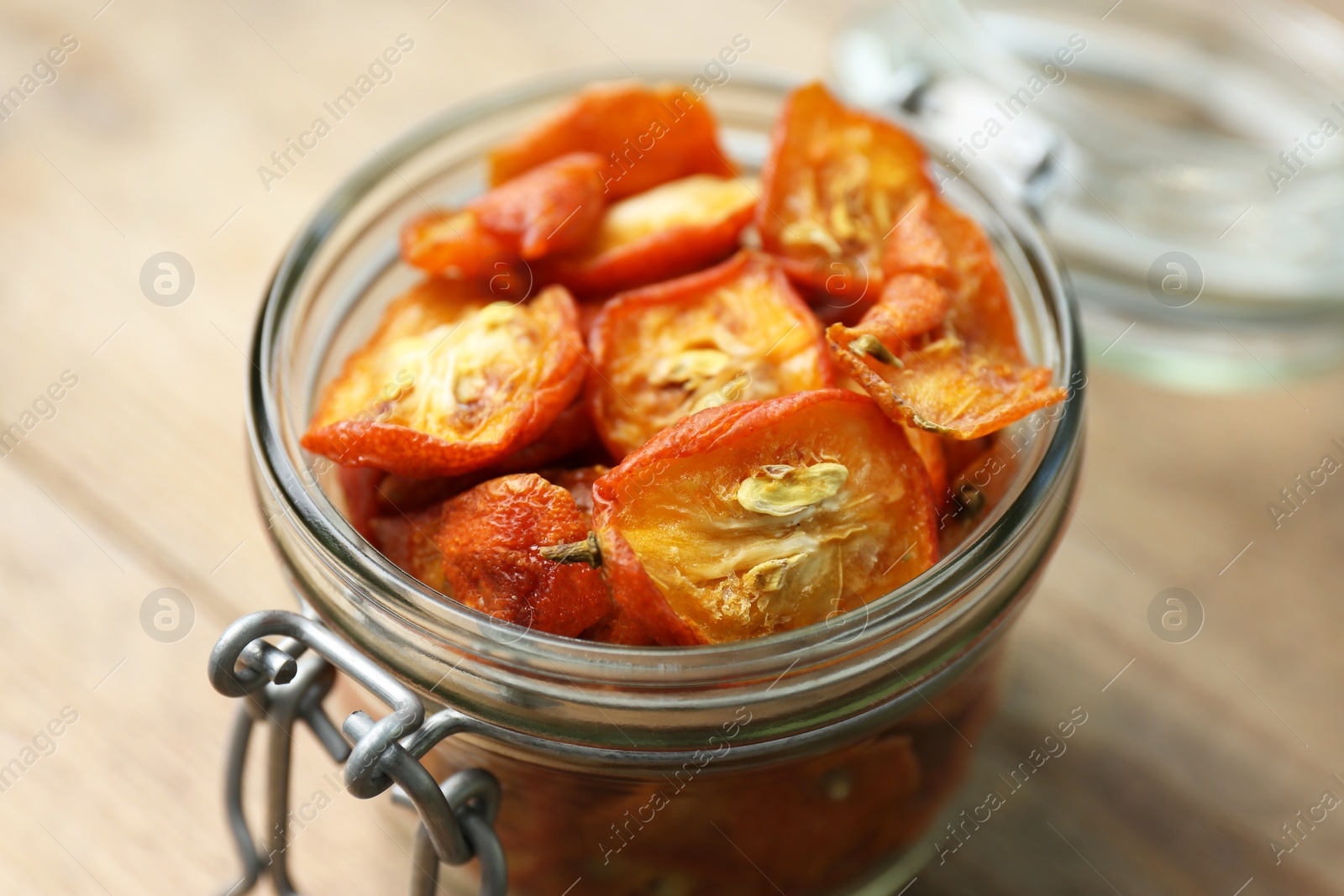 Photo of Glass jar with cut dried kumquat fruits on wooden table, closeup