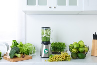 Photo of Blender with delicious smoothie and ingredients in kitchen