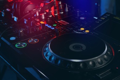Photo of Closeup view of modern DJ controller with headphones