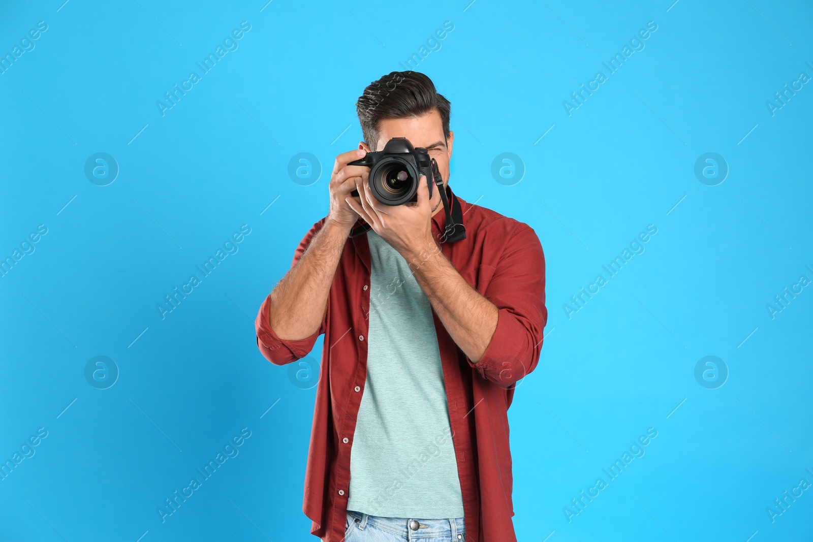 Photo of Professional photographer working on light blue background in studio