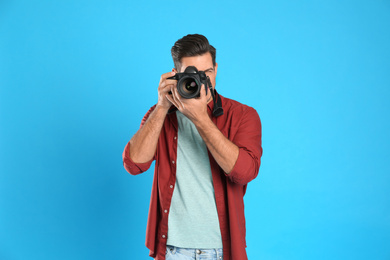 Photo of Professional photographer working on light blue background in studio