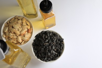 Photo of Bottles of different cooking oils and seeds on white background, above view