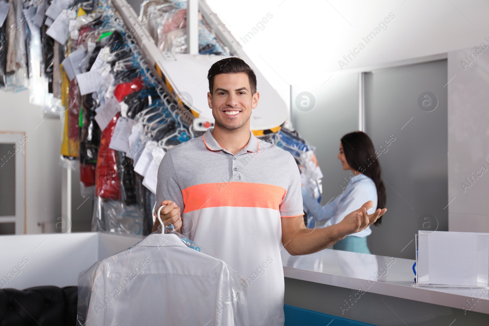 Photo of Happy client with shirt near counter at dry-cleaner's