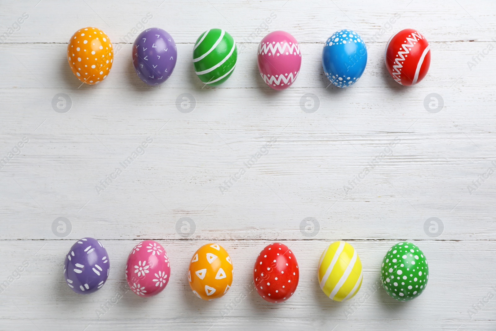 Photo of Decorated Easter eggs and space for text on wooden background, top view