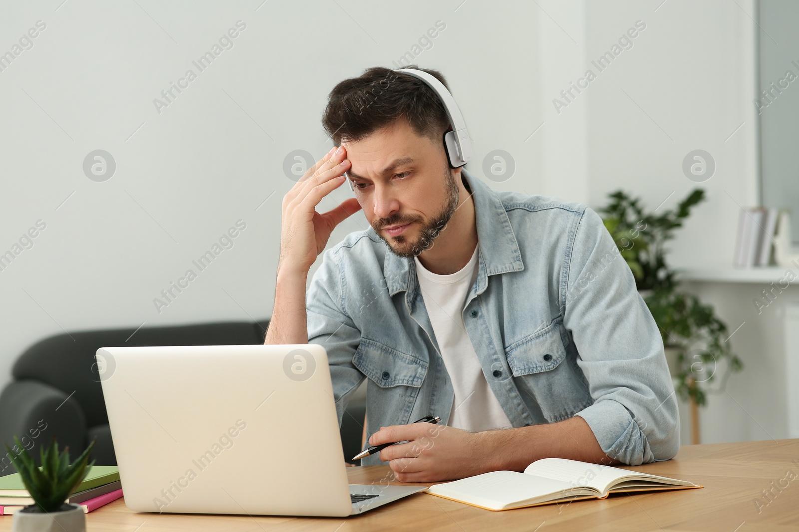 Photo of Man in headphones studying on laptop at home. Online translation course