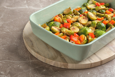Photo of Delicious roasted brussels sprouts with bell pepper and peanuts on marble table