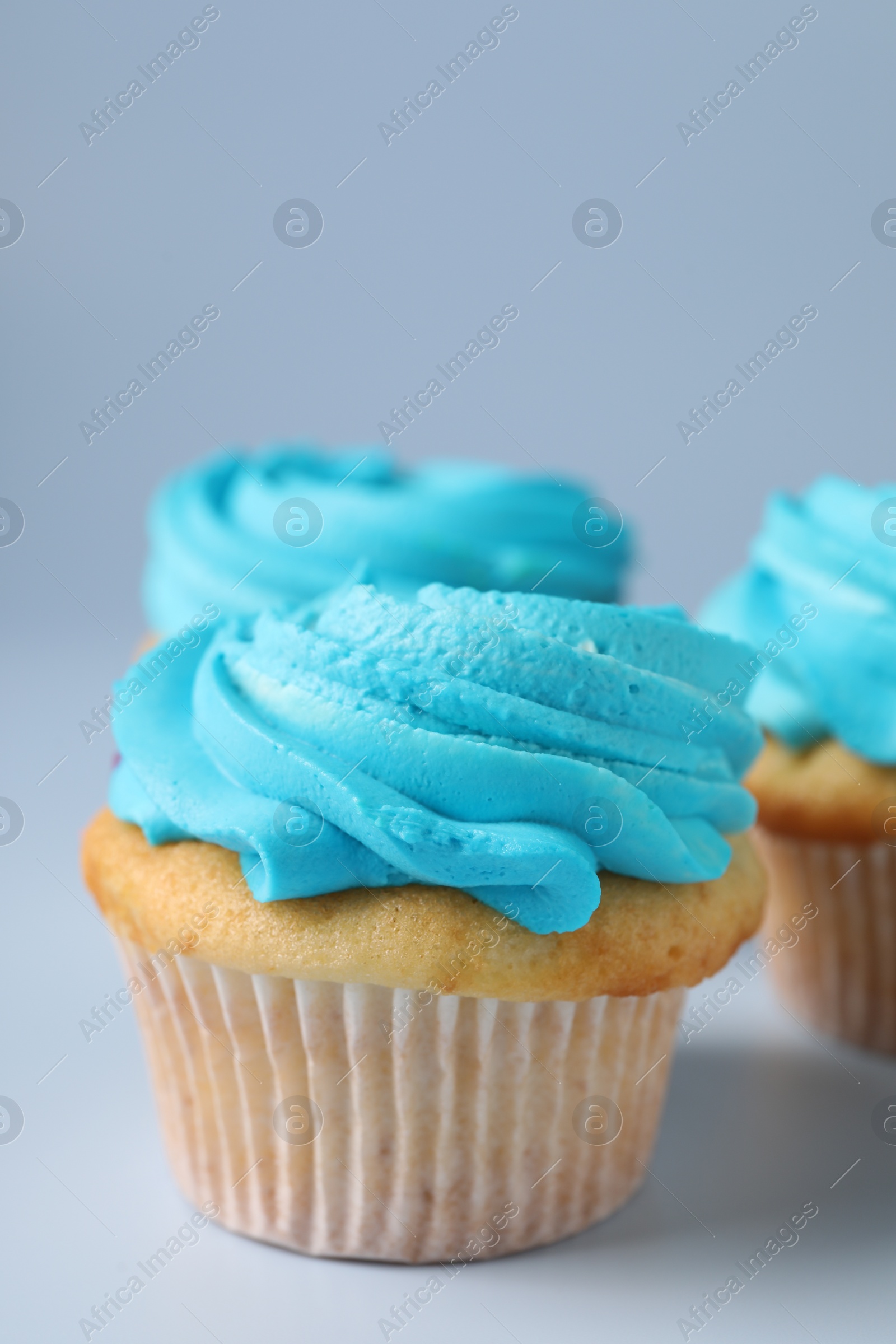 Photo of Delicious cupcakes with bright cream on light background, closeup