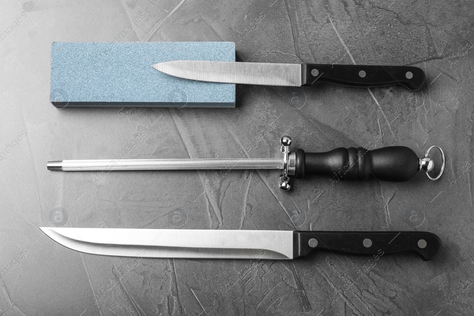 Photo of Flat lay composition with knives and sharpeners on grey background