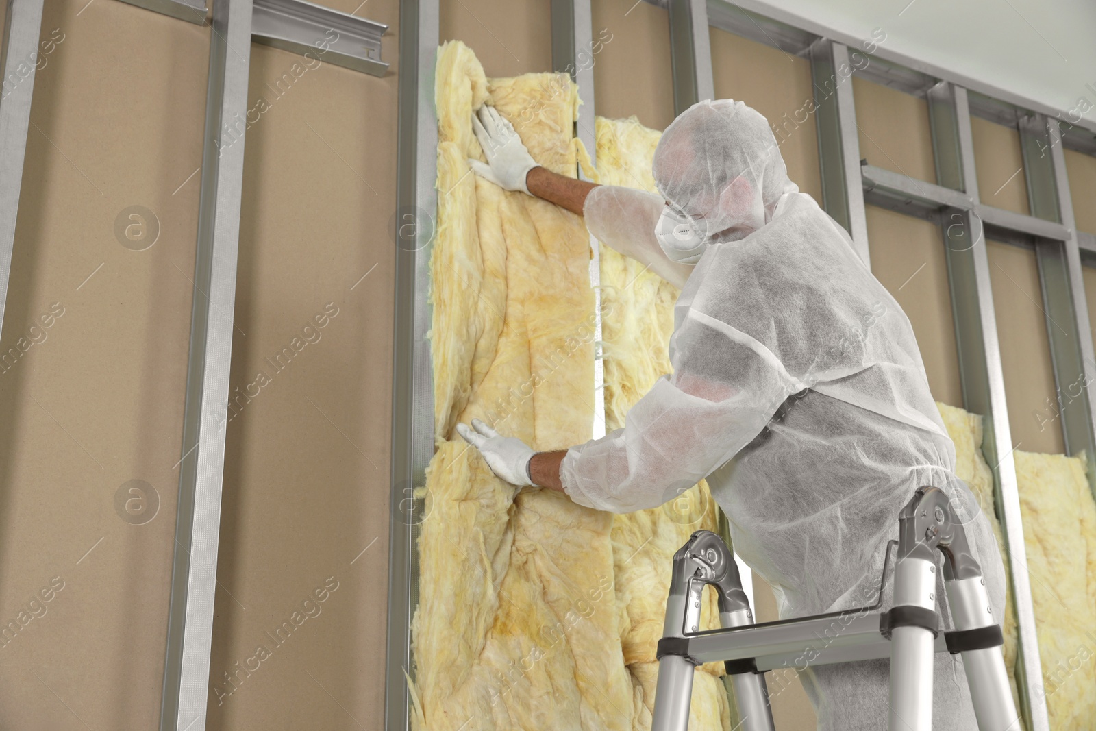 Photo of Worker insulating wall using ladder indoors, low angle view. Space for text