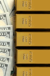 Photo of Shiny gold bars on dollar banknotes, flat lay