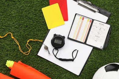 Photo of Different referee equipment on green grass, flat lay